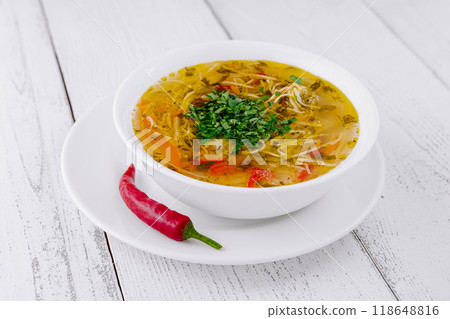 Steaming hot bowl of chicken noodle soup with herbs and spices 118648816