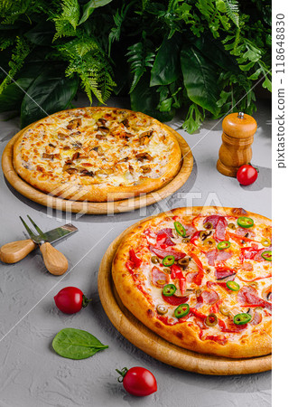 Two delicious pizzas resting on wooden trays, surrounded by fresh ingredients Two delicious pizzas resting on wooden trays, surrounded by fresh ingredients 118648830