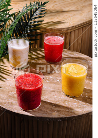 Four colorful smoothies standing on a wooden table in the sunlight 118649064