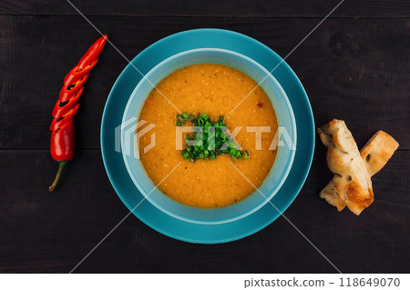 Bowl of soup with bread and chili pepper on wooden table 118649070