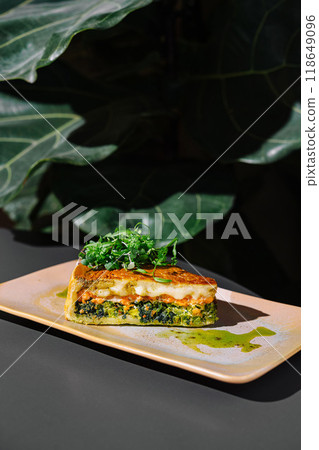 Delicious slice of quiche with salmon and spinach resting on plate 118649096