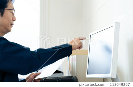 A man in work clothes comparing a computer and documents 118649207