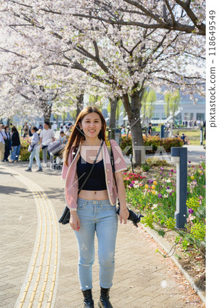 日本東京 — 2024年4月15日:花園裡開著櫻花和女孩。 日本東京 — 2024年4月15日:花園裡開著櫻花和女孩。 118649549