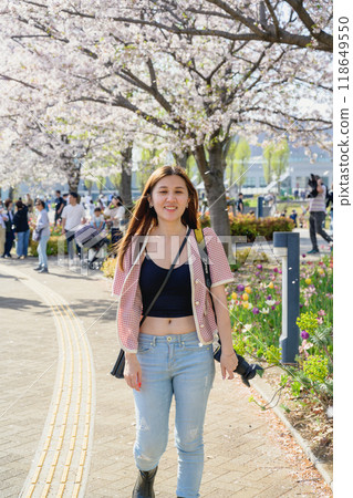 Tokyo, Japan - April 15, 2024: Sakura blossoms and girl in the garden. Tokyo, Japan - April 15, 2024: Sakura blossoms and girl in the garden. 118649550