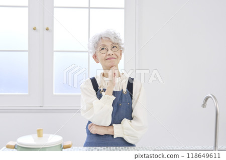 Elderly woman imagining in the kitchen Elderly woman imagining in the kitchen 118649611