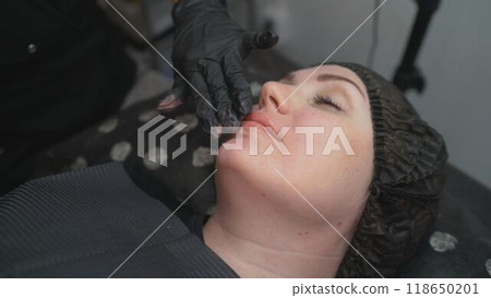 A beautiful dark-haired girl lies on the sofa in the office of the eyelash master. The model lies on the couch in the beauty salon. A beautiful dark-haired girl lies on the sofa in the office of the eyelash master. The model lies on the couch in the beauty salon. 118650201