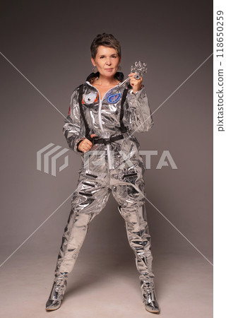 A businesswoman poses in a photo studio in a silver jumpsuit and a black stiletto dress. 118650259
