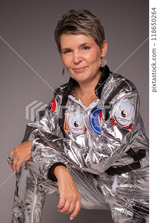 A businesswoman poses in a photo studio in a silver jumpsuit and a black stiletto dress. 118650264
