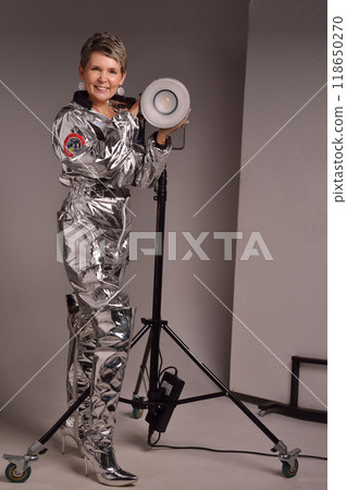A businesswoman poses in a photo studio in a silver jumpsuit and a black stiletto dress. A businesswoman poses in a photo studio in a silver jumpsuit and a black stiletto dress. 118650270