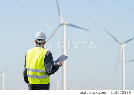 Engineer with digital tablet works on a field of wind turbines 118650589