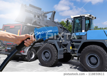 Hand with hydrogen fueling nozzle on a background of fuel cell construction machines. Concept. 118650611