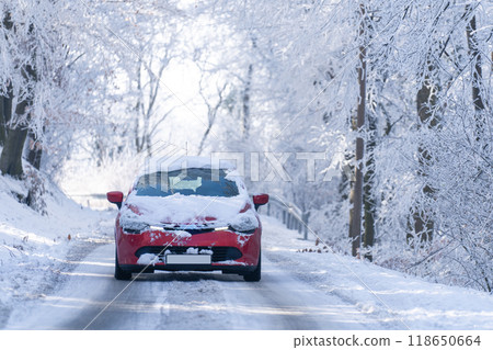 Car on a winter road through a snow covered forest Car on a winter road through a snow covered forest 118650664