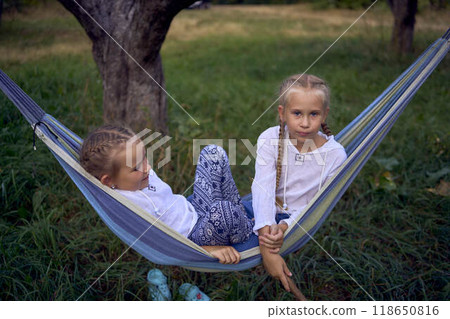 little sisters girls playing together in a hammock, camping with the children little sisters girls playing together in a hammock, camping with the children 118650816