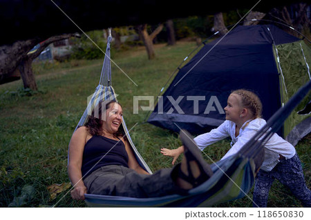 mother with little daughters playing together in hammock, camping with children mother with little daughters playing together in hammock, camping with children 118650830