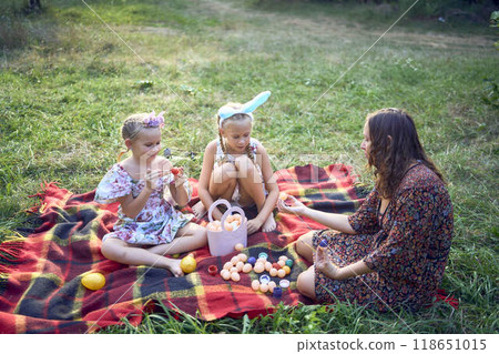 two little girls and mom paint eggs at easter picnic two little girls and mom paint eggs at easter picnic 118651015