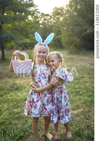 two little girls hug and play bunnies on Easter egg hunt two little girls hug and play bunnies on Easter egg hunt 118651069