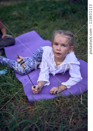 mother and her daughters  roasting and eating marshmallows on  campfire, camping vacation with children, mosquito bites on children's faces 118651113
