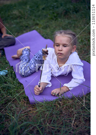 mother and her daughters  roasting and eating marshmallows on the campfire, camping vacation with children, mosquito bites on children's faces 118651114