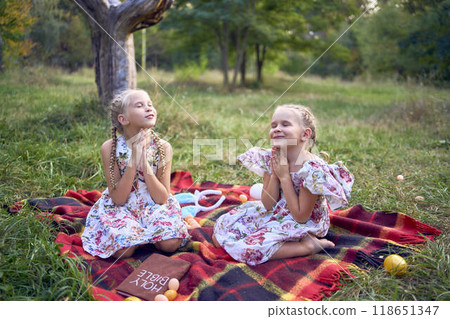 little girls sisters pray to god at easter picnic in garden 118651347