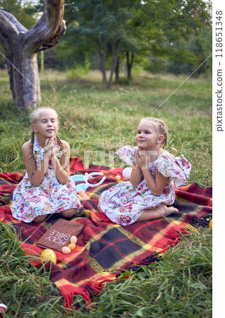little girls sisters pray to god at easter picnic in garden 118651348