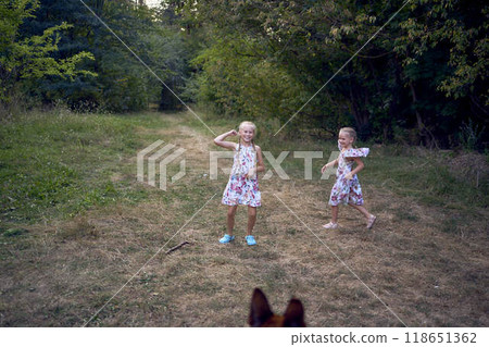 little girls sisters play with german shepherd dog during easter picnic in the garden 118651362