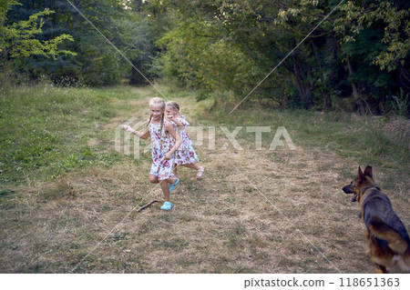 little girls sisters play with german shepherd dog during easter picnic in the garden 118651363