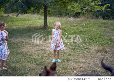 little girls sisters play with german shepherd dog during easter picnic in the garden 118651366
