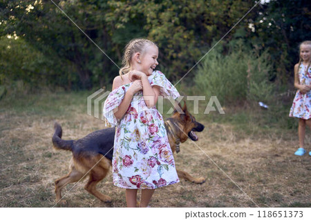 little girls sisters play with german shepherd dog during easter picnic in the garden little girls sisters play with german shepherd dog during easter picnic in the garden 118651373