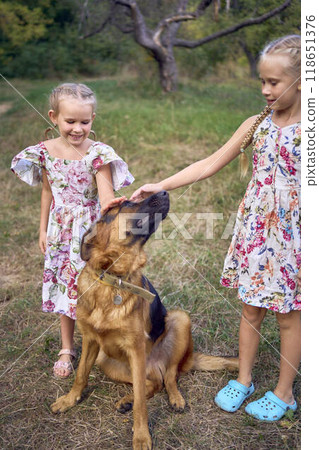 little girls sisters play with german shepherd dog during easter picnic in the garden 118651376