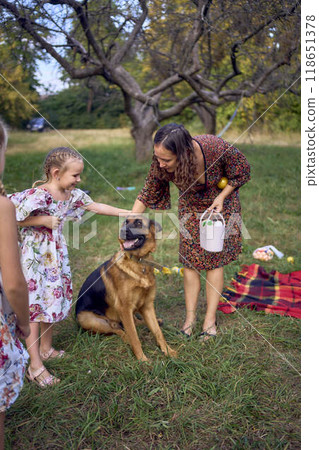 mom and little girls sisters playing with german shepherd dog during easter picnic in the garden 118651378