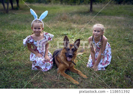 little girls sisters play with german shepherd dog during easter picnic in the garden 118651392