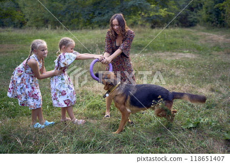 mom and little girls sisters playing with german shepherd dog during easter picnic in the garden mom and little girls sisters playing with german shepherd dog during easter picnic in the garden 118651407