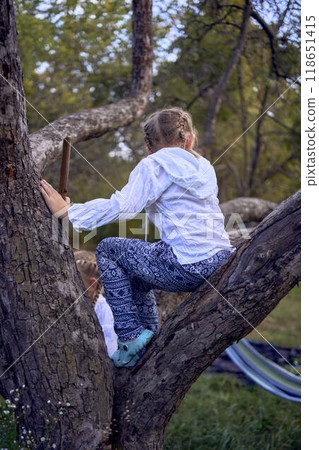 little sisters girls climb a tree, mother secures them below, camping with children 118651415