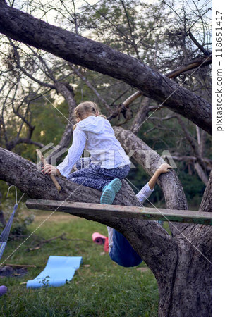 little sisters girls climb a tree, mother secures them below, camping with children little sisters girls climb a tree, mother secures them below, camping with children 118651417