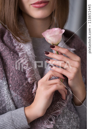 A young woman holds a pink eustoma flower in her hands, close-up 118651445