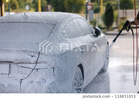 Cleaning car using active foam. Handsome man washing his luxury car on self car-washing Cleaning car using active foam. Handsome man washing his luxury car on self car-washing 118651853