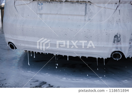 A luxury car covered in white foam at a self-service car wash, waiting. The foam is running down the back of the car A luxury car covered in white foam at a self-service car wash, waiting. The foam is running down the back of the car 118651894