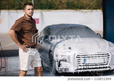 Man stand in front of his luxury car all in white foam on self service car wash. Waiting 118651904