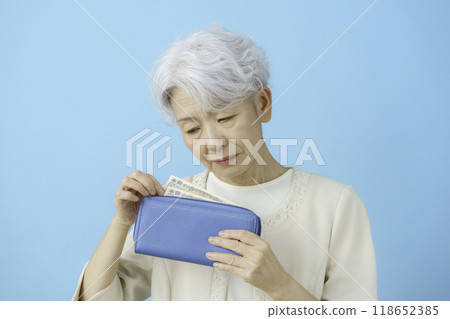 一位老婦人看著錢包裡的錢感到沮喪 118652385