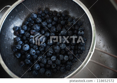 Washing blueberries in a metal strainer in the sink to make a pie. Autumn pastry cooking Washing blueberries in a metal strainer in the sink to make a pie. Autumn pastry cooking 118652572