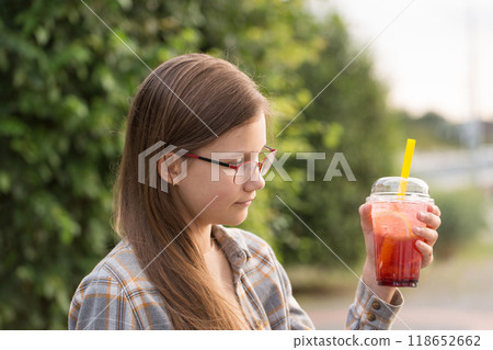 A teenage girl in glasses drinks bubble tea 118652662