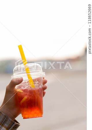 A plastic cup with bubble tea is in the woman's hand A plastic cup with bubble tea is in the woman's hand 118652669