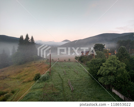 Village in mountains with the view on forest of fir mountains in fog rural horizontal 118653022