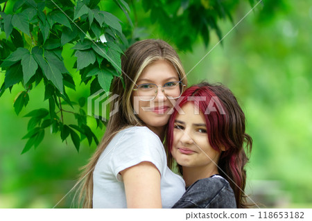 Happy teenager girl friends are hugging and smiling in the park. Happy teenager girl friends are hugging and smiling in the park. 118653182