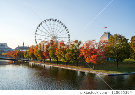 Old Port of Montreal in autumn. Red maples and old Montreal skyline reflected on St. Lawrence River. Fall foliage season in Montreal, Quebec, Canada. La Grande roue de Montreal Ferris wheel. Old Port of Montreal in autumn. Red maples and old Montreal skyline reflected on St. Lawrence River. Fall foliage season in Montreal, Quebec, Canada. La Grande roue de Montreal Ferris wheel. 118655394