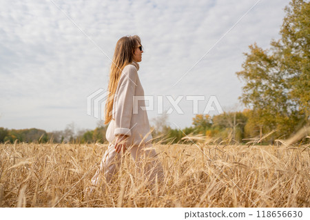 A Stylish Woman is Enjoying a Beautiful Sunny Day in the Middle of a Wheat Field 118656630