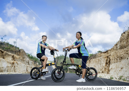male and female biker riding bike on road male and female biker riding bike on road 118656957