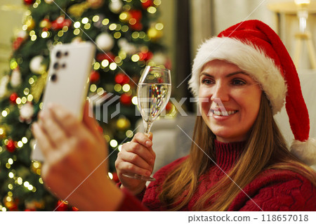Woman with Santa hat taking selfie near Christmas tree Woman with Santa hat taking selfie near Christmas tree 118657018