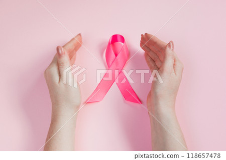 Breast Cancer Awareness Month. Woman's hand holds pink ribbon. Health care concept, cancer control symbol. Copy space. 118657478
