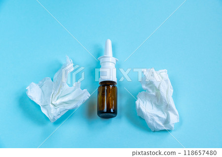Nasal spray for runny nose and crumpled paper tissues on blue background. Season of colds and illnesses 118657480